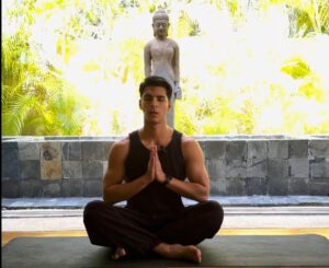 Screenshot of yoga instructor Mauricio sitting in a calm starting position on a yoga mat outdoors for a Livana Life Stress Session
